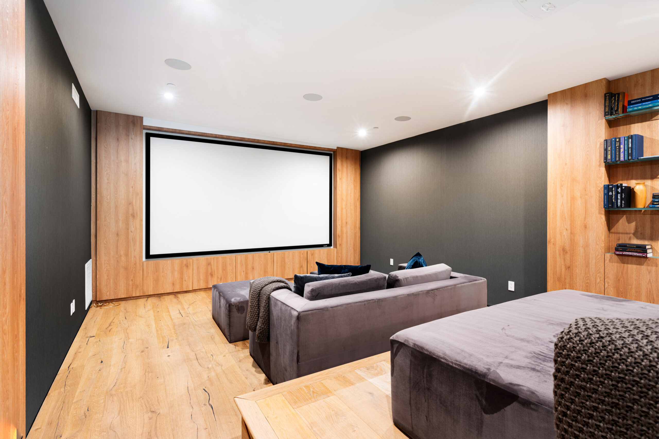 A spacious room featuring a large grey sofa beside a white screen
